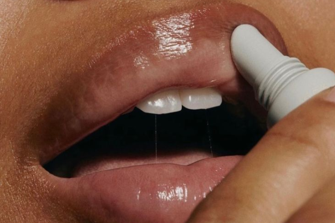 Close-up of a person applying lip balm to their lips with a white applicator.